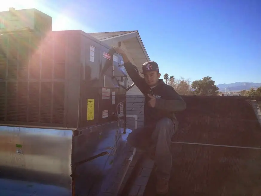 HVAC technician performing Air Duct Cleaning on a rooftop unit in Weare
